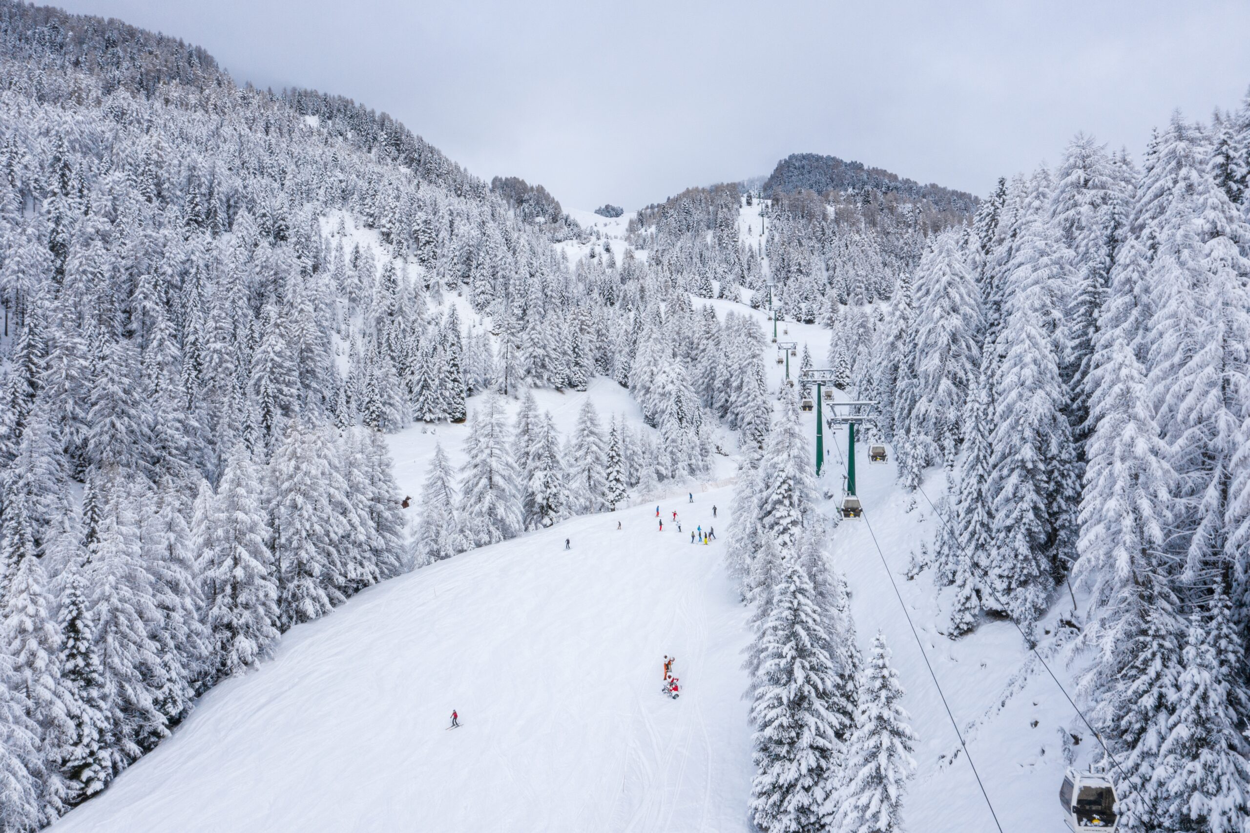 An aerial shot of a skiing track in a snowy landscape under the sunlight